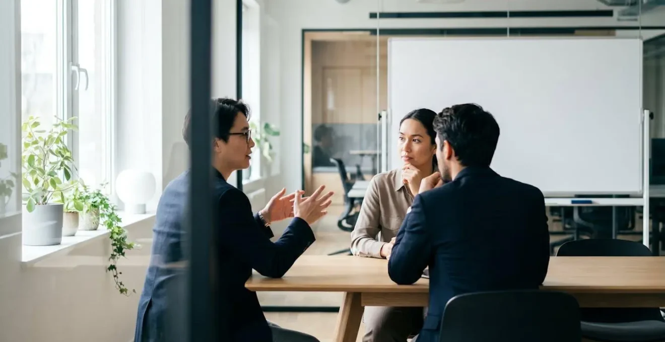 Two business professionals in side view having a focused discussion at an office table with natural lighting